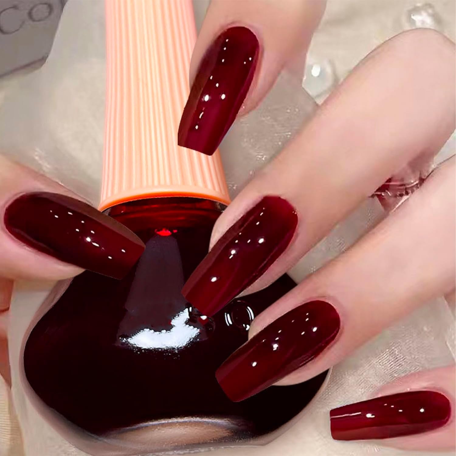 Helia Φωτεινό βερνίκι νυχιών in deep red shade, showcasing glossy finish and well-manicured long nails.