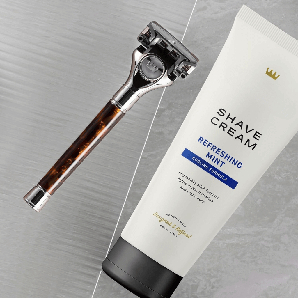 Helia δροσιστική κρέμα ξυρίσματος and razor on a marble surface, showcasing premium shaving gear.
